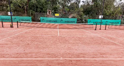 Court de tennis en terre battue vu derrière la ligne de fond